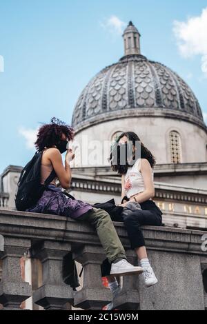 Londra / UK - 06/13/2020: La protesta contro la questione delle vite nere durante la pandemia di coronavirus. Due ragazze bianche che si siedono sul balcone di Trafalgar Square Foto Stock