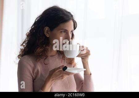 Bella giovane donna che beve il tè, guardando la finestra Foto Stock