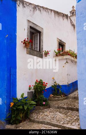 Óbidos, Portogallo - famosa destinazione turistica per la sua architettura e la sua storia - Case tradizionali dai colori vivaci con fiori Foto Stock