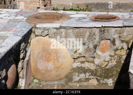 Roman Grande Taberna (fast food) con bancone rivestito in marmo e contenitori in ceramica argilleria nell'antica città di Ercolano, Italia Foto Stock
