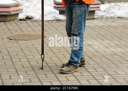 Lavoratore con un picchio di ghiaccio tra le mani libera il cortile interno tra le case da sporcizia, neve e ghiaccio Foto Stock