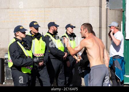 Un controricomprettore di estrema destra affronta un ufficiale di polizia accanto a Westminster Bridge, Londra, il 13 giugno 2020 Foto Stock