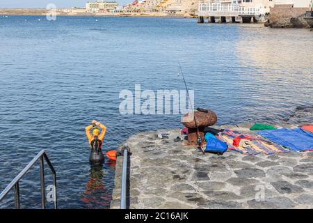 I residenti locali hanno la spiaggia a se stessi come il tempo si fa salire per l'estate. Il nuotatore in acqua aperta entra in mare. Fase 3 de-escalation del co Foto Stock