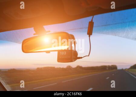 Vista del sedile anteriore della strada, dello specchietto retrovisore e del registratore di velocità in condizioni di luce solare. Movimento sfocato Foto Stock