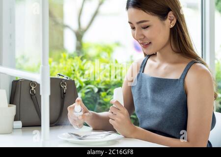 Asian attraente donna che spruzzano alcool su stoviglie in ristorante per pulire ridurre l'infezione di coronavirus covid-19. Nuovo stile di vita normale al restau Foto Stock