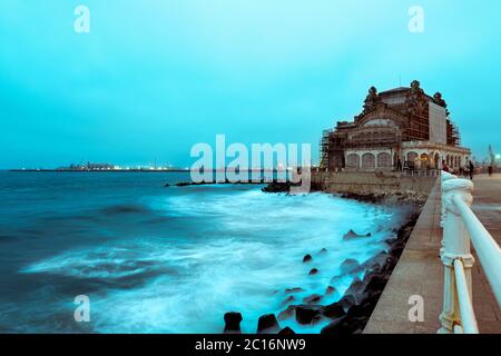 Il vecchio casinò di Constanta, Romania, sulla costa del Mar Nero all'alba. Belle onde schiumose che si infrangono sulla riva Foto Stock