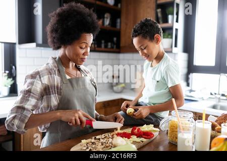 Felice madre e bambini in cucina. Cibo sano, famiglia, concetto di cucina a vista Foto Stock