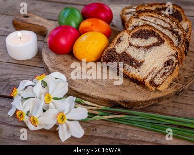 tradizionale rumeno piatto pasquale cozonac o animelle su tavola di legno e colorato uova di pasqua e fiori Foto Stock