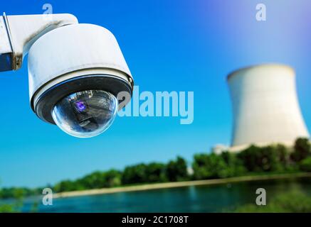 Immagine ingrandita della telecamera di sicurezza TVCC e della centrale atomica sfocata sullo sfondo Foto Stock