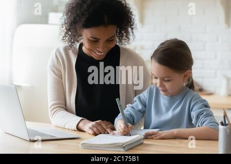 Tutor africano impegnato con studentessa caucasica aiutare a completare i compiti Foto Stock