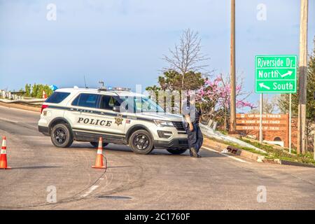 04 06 2019 Tulsa USA - Tulsa cop si appoggia sulla parte anteriore della sua macchina di polizia bloccando il cavalcavia con coni arancioni in giornata con ringhiera danneggiata dietro e. Foto Stock