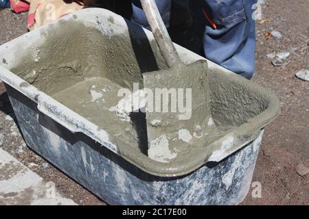 L'operaio inginocchiato cemento per fissare la fondazione del supporto sotto i semafori vicino alla strada con l'aiuto di un bagno e. Foto Stock