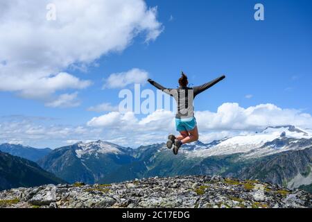 Donna allunga le braccia in Jump in Cascades Nord Foto Stock