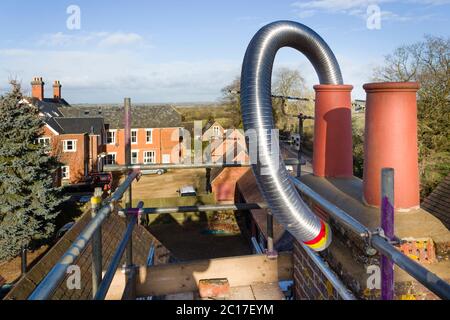 Installazione di un tubo flessibile in acciaio canna fumaria in un camino durante un'installazione di stufa a legna, UK Foto Stock