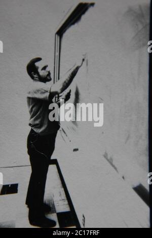 Fine anni 70 vintage in bianco e nero fotografia estrema di un insegnante in piedi alla lavagna e di scrittura su di esso. Foto Stock