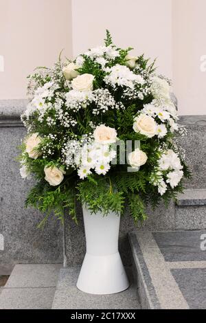 Un bouquet floreale di rose crema e crisantemi all'ingresso della chiesa come decorazione della vacanza. Professionale fl Foto Stock