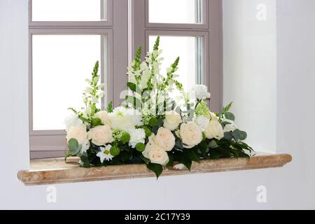 Un bouquet di fiori di rose crema e crisantemi sulle finestre della chiesa come decorazione della vacanza. Flo professionale Foto Stock