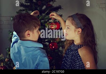 Felici i bambini decorare l'albero di Natale in bel soggiorno con un tradizionale camino. Foto Stock