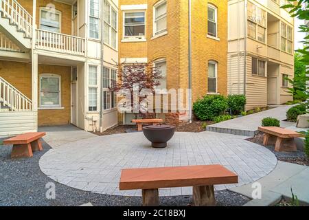 Panchine di pietra intorno al camino fuori di un complesso residenziale Foto Stock
