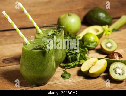 Frullato verde appena miscelato in bicchieri con padelle. Sfondo di legno. Foto Stock