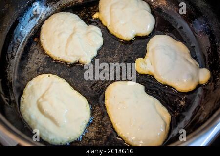 l'impasto viene fritto in una padella nera, cosparso di olio in tutte le direzioni, sporcandola la stufa e tutta la cucina Foto Stock