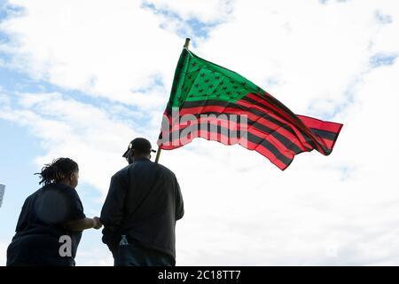 Una coppia vola con una bandiera panafricana in una marcia a sostegno del movimento Black Lives Matter nel quartiere High Point di Seattle domenica 14 giugno 2020. Foto Stock