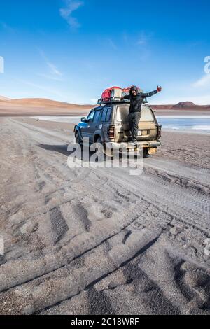 giovane uomo marrone che si trova sulle spalle di un suv nel deserto della bolivia Foto Stock