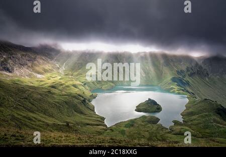 raggi di sole attraverso le nuvole sul lago alpino Foto Stock
