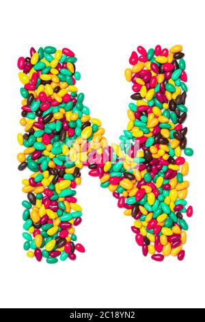 Lettera N dell'alfabeto inglese da cioccolatini rotondi multicolore su sfondo bianco isolato. Modello di cibo fatto da caramelle per bambini. Luminoso Foto Stock