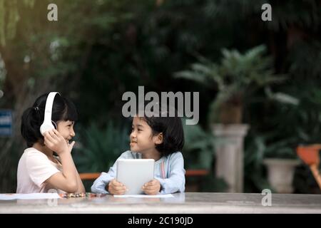 Due ragazze asiatiche bambini stanno ascoltando la musica dallo smartphone in giardino. Foto Stock