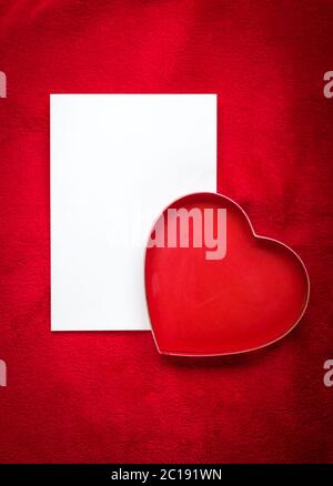 cuore con una carta vuota su sfondo rosso Foto Stock