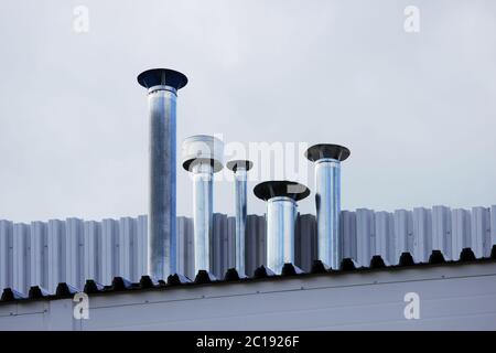 Cinque tubo camino in acciaio inox sul tetto della casa. Foto Stock