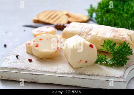 Porzioni di burro di erbe con pezzi di pepe dolce per panini e bistecche tagliate su un pannello di legno. Piatti italiani fatti in casa Foto Stock