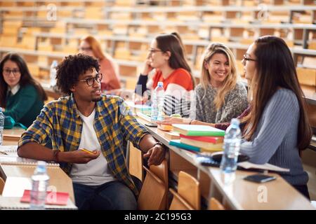 Giovani studenti di freschissimo che parlano e sorridono in anfiteatro Foto Stock