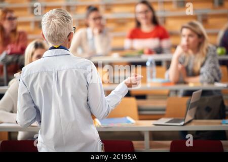 Professore anziano che dà una lezione agli studenti in anfiteatro Foto Stock