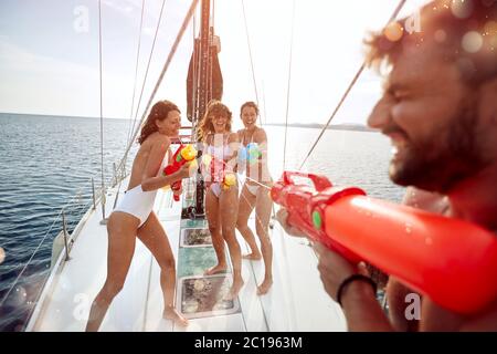 Gruppo di amici gioca a vela con pistole d'acqua. Foto Stock