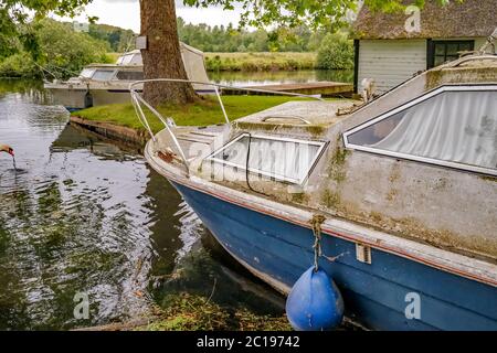 Motoscafo privato di proprietà in disperata necessità di riparazione e ristrutturazione ormeggiato in una diga privata al largo del fiume Bure nel villaggio Norfolk di Coltis Foto Stock