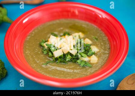 Minestra di crema, broccoli, melanzane, zucchine in una targhetta rossa, olio di oliva, prezzemolo formaggio Foto Stock