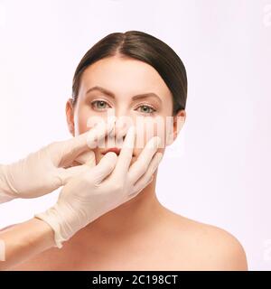 Consultazione medica plastica. Mani del medico. Faccia della donna Foto Stock