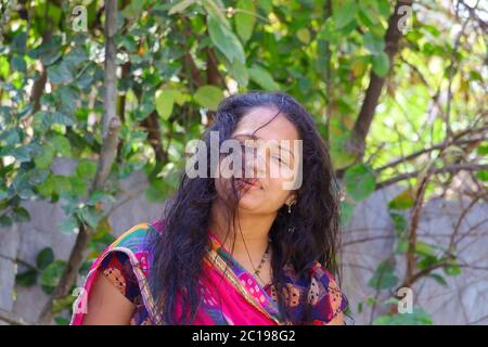 Vista frontale di una giovane ragazza indiana che si trova nel giardino di casa Foto Stock