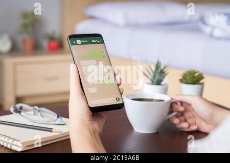 donna mano che tiene lo smartphone mobile con schermata mockup del messaggio di chat sull'applicazione di social media. modello della finestra di dialogo bolla vocale Foto Stock