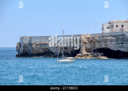 Barca a vela nel mare azzurro sulla costa di Polignano a Mare, Puglia, Italia Foto Stock