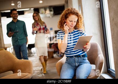 Donna di affari con un tablet, i suoi colleghi discutono di questioni aziendali in background Foto Stock