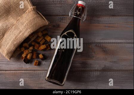 Vista dall'alto in casa tradizionale russo kvass in bottiglia e cracker in una borsa su sfondo di legno. Ottima bevanda rinfrescante per l'estate Foto Stock