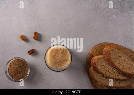 Vista dall'alto in casa tradizionale russo kvass in vetro con schiuma e pane sul tagliere su sfondo chiaro. Ottima bevanda rinfrescante per l'estate Foto Stock