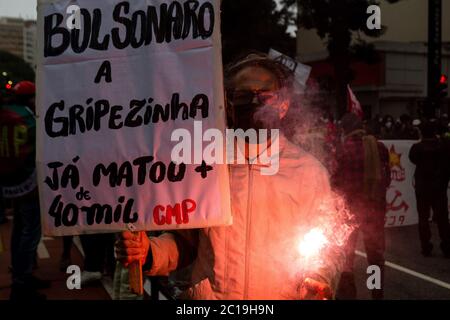 San Paolo, Brasile. 14 Giugno 2020. "Bolsonaro, la piccola influenza ha già causato più di 40,000 morti", dice sulla bandiera di un dimostratore. A San Paolo, la polizia militare ha stimato che 1000 dimostranti si sono riuniti nel frizzone in un'azione di protesta contro Bolsonaro, contro il razzismo e per la democrazia. Credit: Diego Baravelli/dpa/Alamy Live News Foto Stock