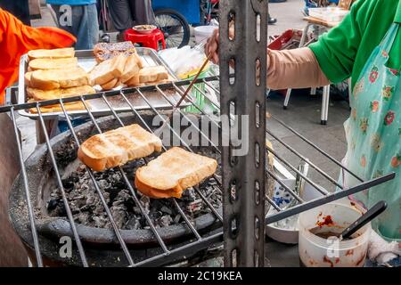 Gustosi piatti di strada sono cucinati su carbone nel centro di Bangkok, Thailandia Foto Stock