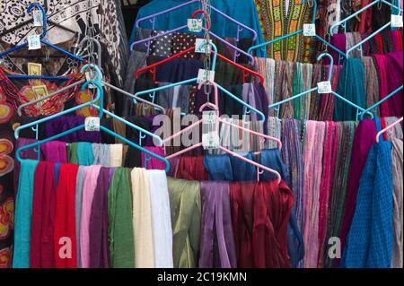 Abiti colorati e scialli con le etichette di prezzo scritte a mano appese su un appendiabiti di plastica su un mercato a Faversham, Regno Unito Foto Stock