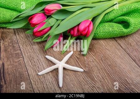 Starfish e tulipani rossi su una tavola di legno Foto Stock