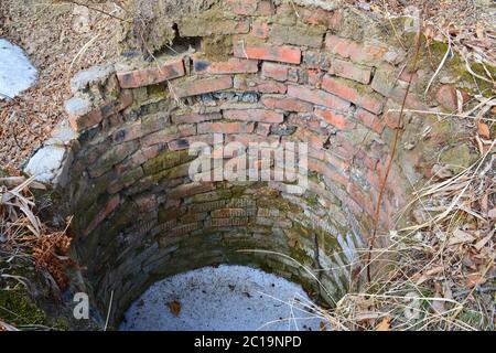 Un vecchio pozzo abbandonato in mattoni in inverno Foto Stock